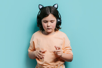 Young girl wearing cat ear headphones against blue background