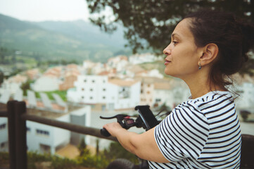 Close-up side portrait of a young multi ethnic woman cyclist in white and black striped t-shirt,...