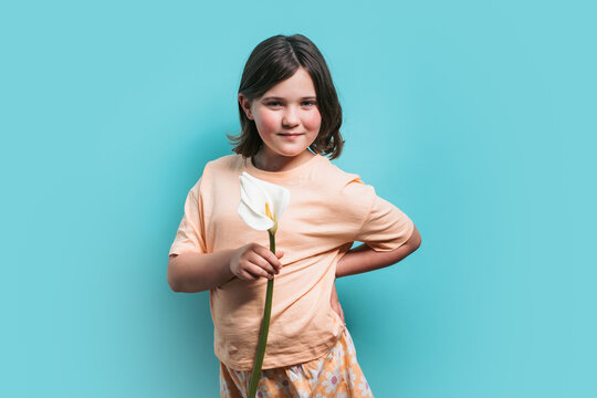 Smiling young girl holding a white calla lily on a blue background