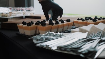 Catering service preparing dessert table with panna cotta and blackberries