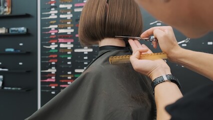 Hairdresser trimming brown hair with scissors at salon