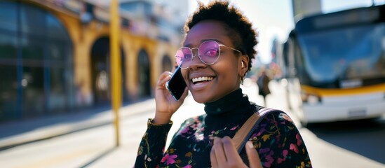 afro woman talking on mobile phone on the street smiling