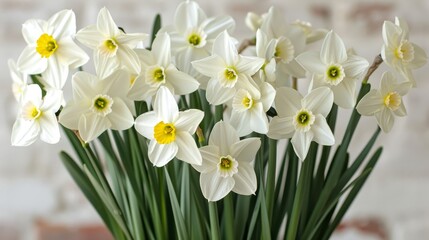 Obraz premium A vase holds white and yellow blooms atop a weathered wooden table against a brick wall backdrop