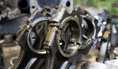 connecting rods of a car engine against the background of a disassembled engine