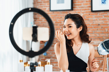 Woman influencer shoot live streaming vlog video review makeup uttermost social media or blog. Happy young girl with cosmetics studio lighting for marketing recording session broadcasting online. - obrazy, fototapety, plakaty