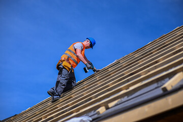 Repair and replacement of the old roof with a new one. Construction worker in protective clothing...