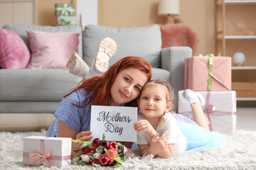 Mother and child lying on floor and card with text MOTHER'S DAY in living room