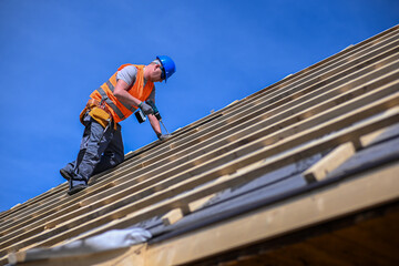 Repair and replacement of the old roof with a new one. Construction worker in protective clothing...
