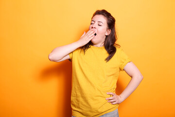 Portrait of caucasian woman yawning and covering her mouth, feeling sleepy in studio. Tired female...