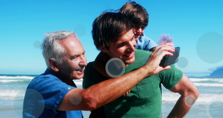 Caucasian family enjoying time at beach, grandfather, father, and grandson smiling
