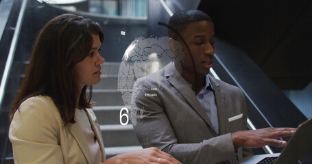 Diverse couple, both looking at laptop on staircase