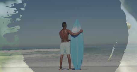 African American male holding surfboard on beach