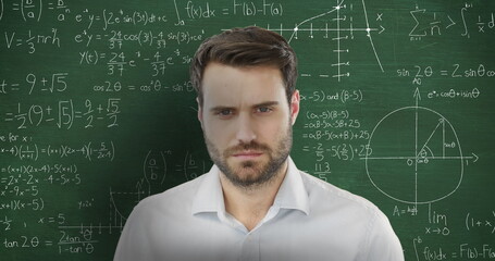White man, short brown hair, and beard in front of chalkboard with equations