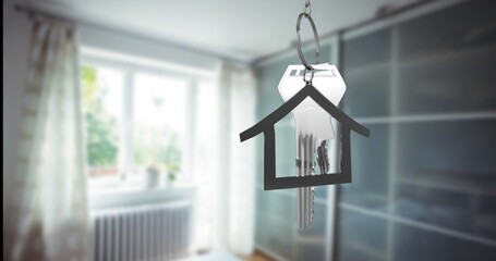 A keychain in shape of house containing keys hanging in focus