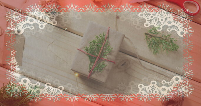 Two gifts wrapped in cloth lie on pink surface, adorned with pine twigs