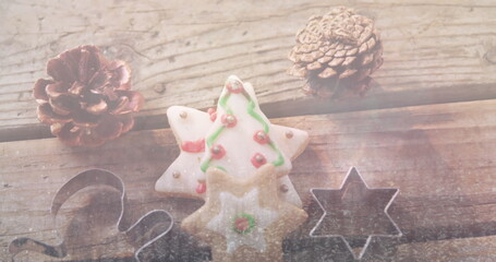 Fototapeta premium A star-shaped cookie with green and red icing sits between pine cones