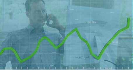 Caucasian male talking on phone, looking at graphs