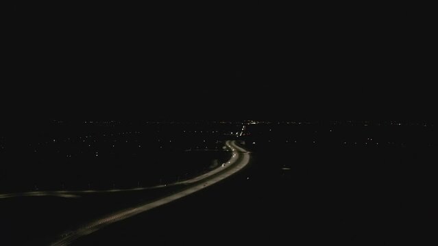 Aerial footage of a roundabout on the expressway at night and city lights in the background