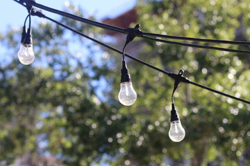 Selective focus shot of string lights with light bulbs hanging in a city