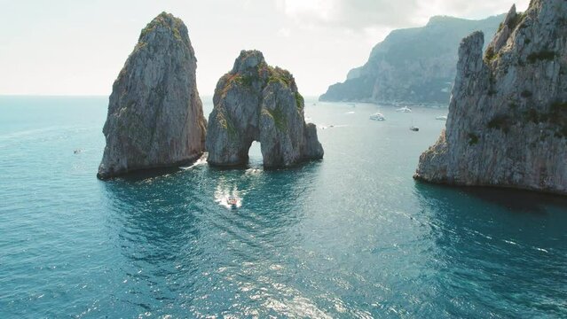 Capri sea stacks create a stunning gateway in the Tyrrhenian Sea. Aerial view of world famous Faraglioni cliffs in summertime.