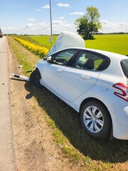 The car displays deployed airbags and front-end damage with scattered debris, revealing the...
