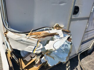 The caravan sustained significant structural damage on its side from the impact, creating a chaotic and hazardous environment.