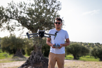 Brunette youth, sunglasses-clad, expertly operates drone to capture breathtaking aerial vistas.