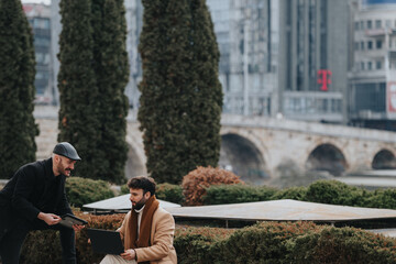 Two professionals engaging in a discussion with a laptop in an urban park setting, showcasing a relaxed business atmosphere.