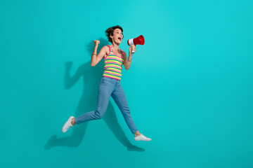 Full length photo of overjoyed person jump raise fist communicate loudspeaker empty space isolated...