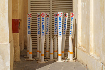 Close-up view of several plastic signs, pillars with a no parking sign standing in a corner of the...