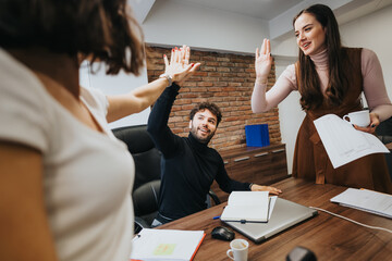 Enthusiastic team giving high-fives in a collaborative office setting, expressing teamwork and success.