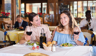 Two positive females dining in restaurant, enjoying meal and conversation