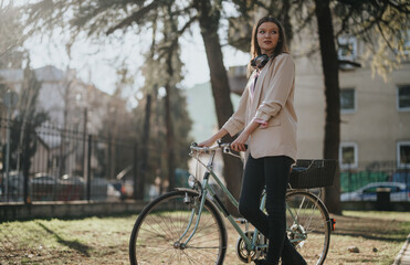 A young woman stands with her vintage bicycle in a sunny urban park, exuding casual style and elegance amidst nature.