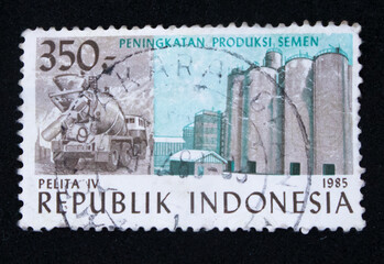 Old philatelic postage stamp with an illustration of an Indonesian cement factory - obrazy, fototapety, plakaty