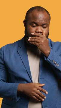 Vertical video African american man covering mouth in disbelief, feeling upset by events, isolated over studio background. BIPOC person shaking head, left speechless by troubling news, camera A