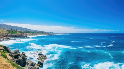 Beautiful seascape with bright blue water, white waves crashing on rocky coast, and green hills in the distance.