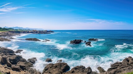 Obraz premium Rocky coast with blue sea and clear blue sky with white clouds in the background.