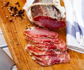Outdoor kussens Smoked pork tenderloin sliced on wooden cutting board. Cured pork meat. © JackF