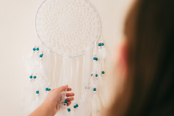 Dream Catcher.girl hangs a white dream catcher on the wall.Decoration for home and room. Macrame...