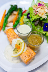Seared salmon steak with Fresh Salad Leaf on a white plate in a restaurant
