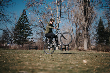 A dynamic scene of a young man effortlessly performing a wheelie on his bicycle in a beautifully lit park, capturing a moment of joy and freedom.