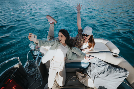Two happy young women capture a moment of fun with a selfie aboard a boat on a bright, sunny day.