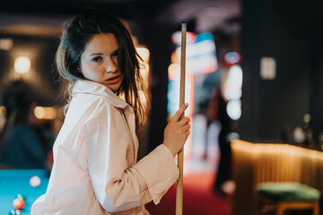 A young woman enjoying a game of billiards with friends at a cozy bar, embodying happiness and togetherness.