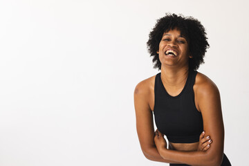 Biracial woman laughing in studio, wearing black sportswear, copy space - 788839811