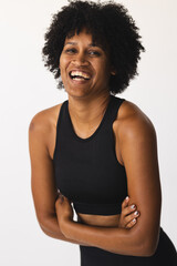Biracial woman with curly hair laughing in studio, wearing black sportswear - 788839813