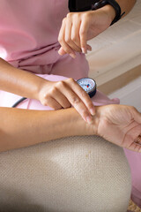 Mature biracial woman checking blood pressure at home, young biracial female nurse watching - 788839815