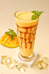 Mango juice on juice glass with mango fruit and ice cube and mint leaf