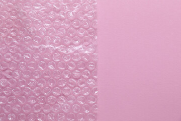 Transparent bubble wrap on pink background, top view. Space for text