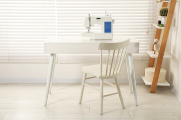Sewing machine on white desk near chair indoors