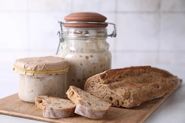 Fotobehang Sourdough starter in glass jars and fresh bread on light table © New Africa